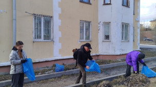 на фото три человека с мусорными мешками наводят порядок на территории