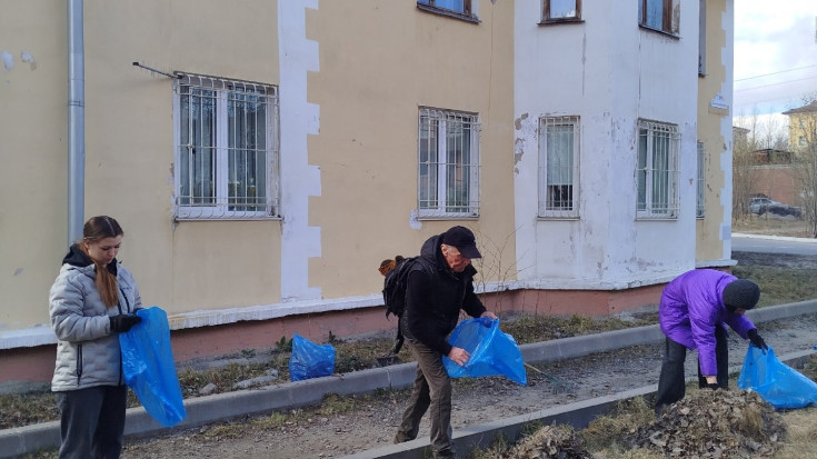 на фото три человека с мусорными мешками наводят порядок на территории